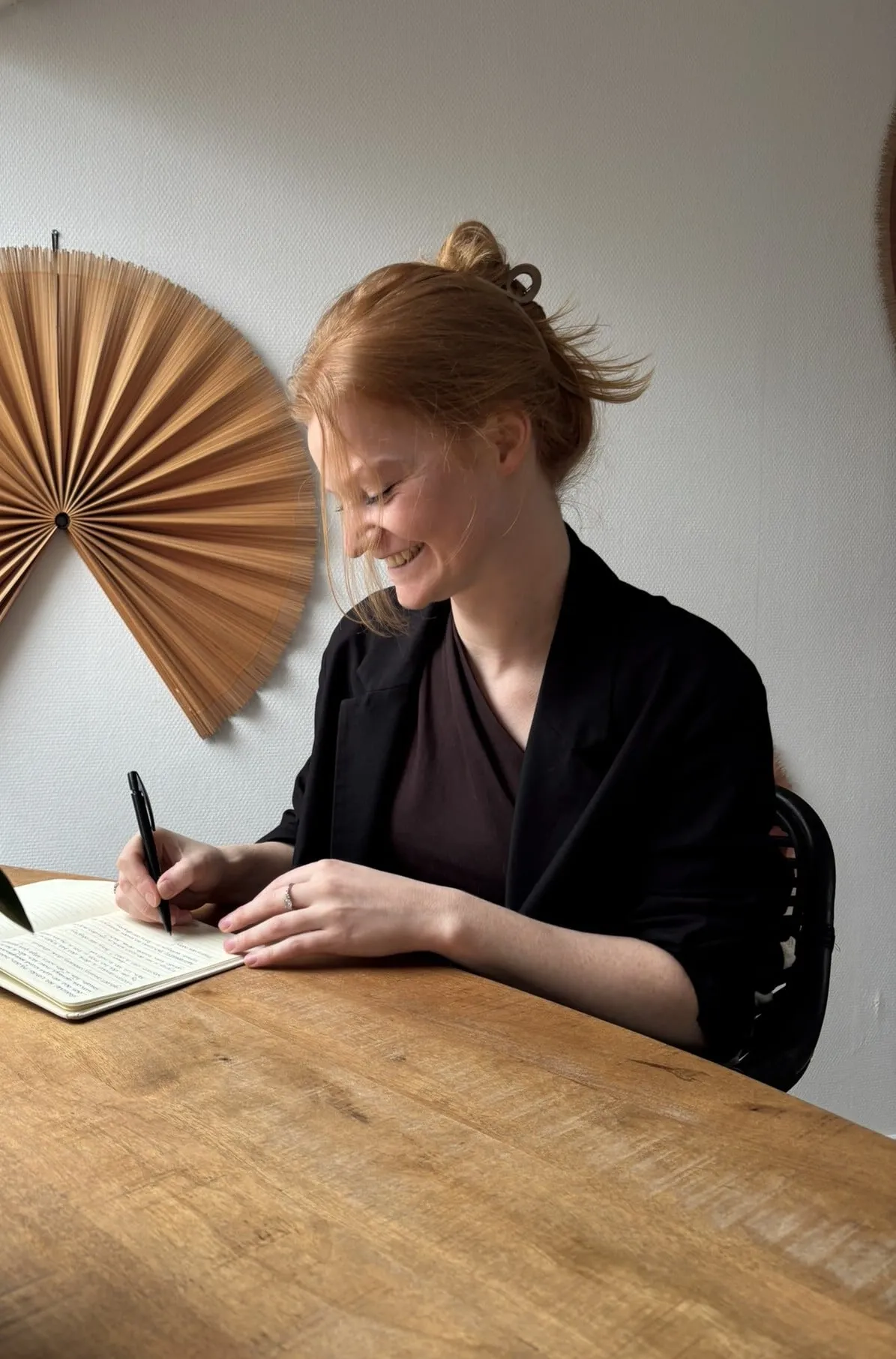 Celine Pranger aan het werk aan tafel, schrijvend in een notitieboek